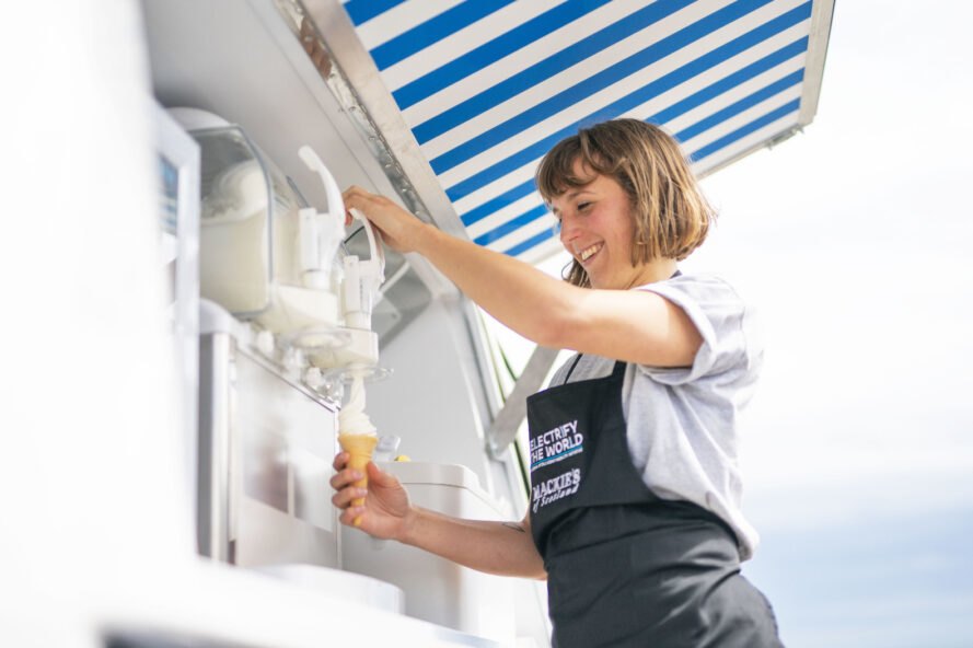 woman making ice cream cone next to a van