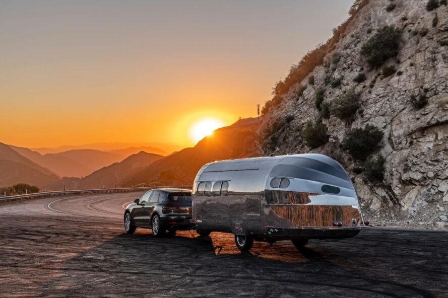 sun rising over mountains and reflecting off an aluminum travel trailer