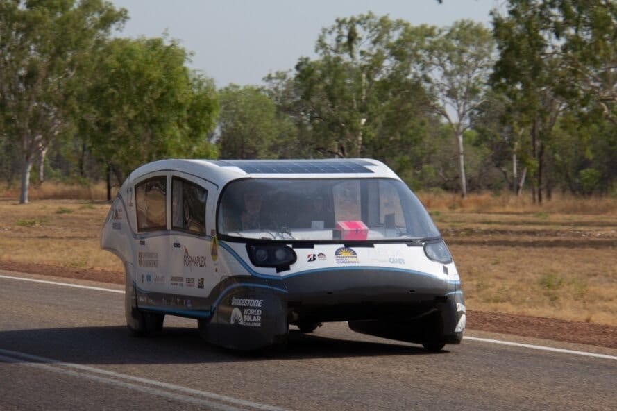 white solar-powered electric car driving down a road