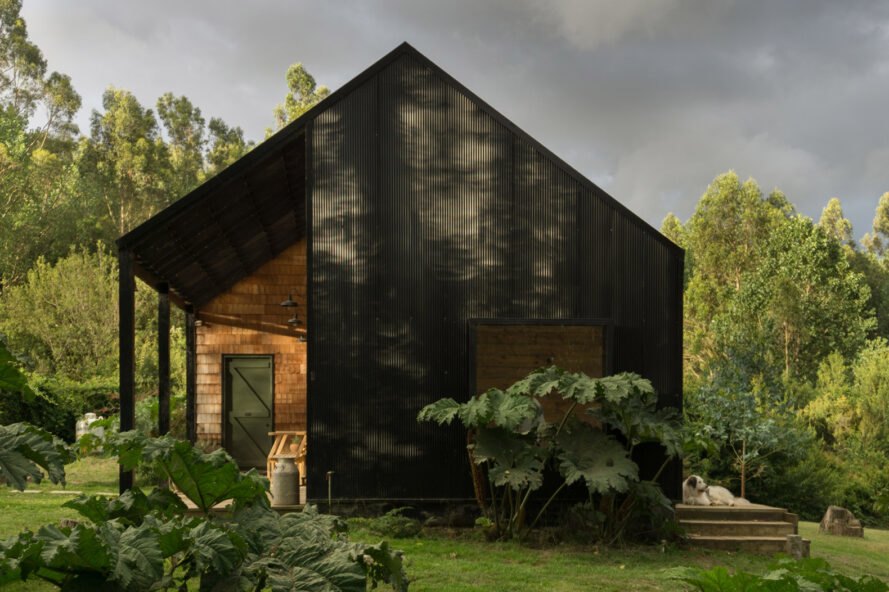 black gabled home with small, light wood porch