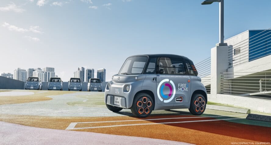 tiny gray electric car with logos on the door